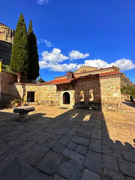 a stone building with a stone bench and trees